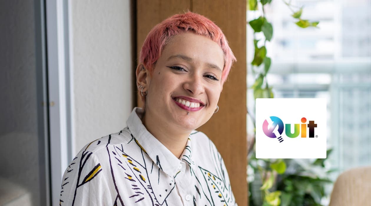 A young person with rose coloured hair facing the camera