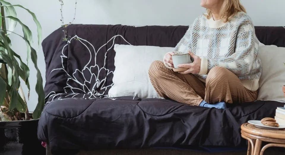 Image of a lady sitting on a couch with a cup of tea