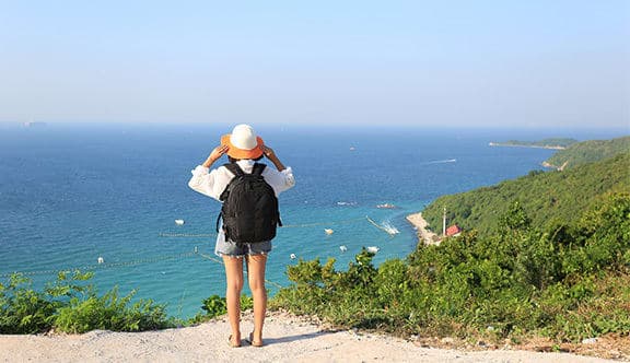 A woman in a hat looks out onto the ocean