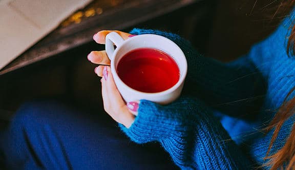 Two hands holding a cup of tea