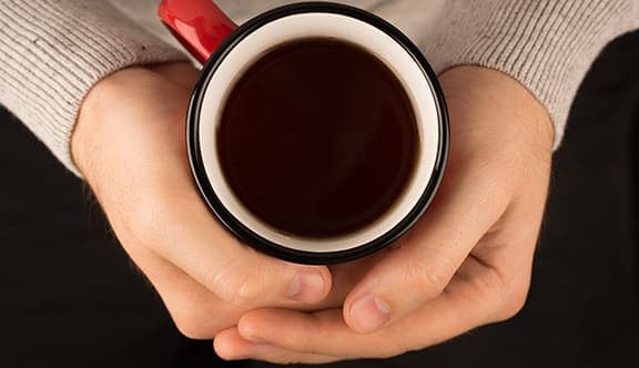 Two hands holding a mug of coffee
