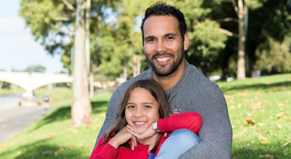 A father and daughter sitting outside smiling